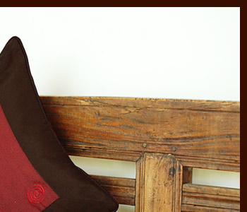 レッドを基調としたクッションカバーは表面の異なる色の渦巻きの刺繍が特徴的。